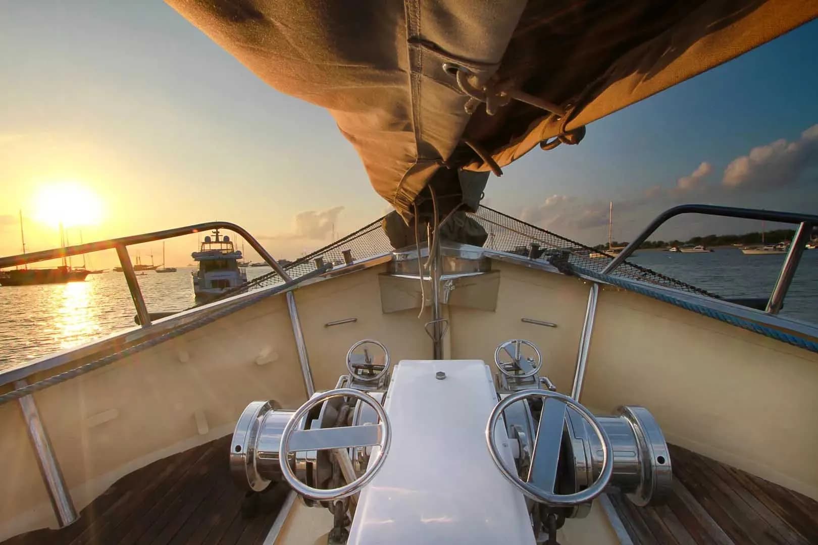 A view of the bow of the Adelaar boat silhouetted against a vibrant sunset sky.