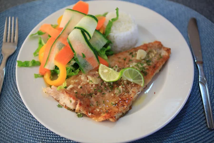 A plate holds a filet of fish, rice, and vegetables aboard the MV Valentina liveaboard.